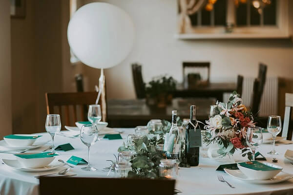 Zastawiony i przystrojony w eleganckie stroiki dla rodziny i ich znajomych w momencie komuni, Na stole znajduje się przykłdowe ułożenie dla wszystkich gości